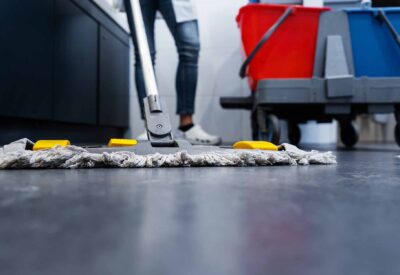 Low shot of cleaning lady mopping the floor in restroom beside her trolley